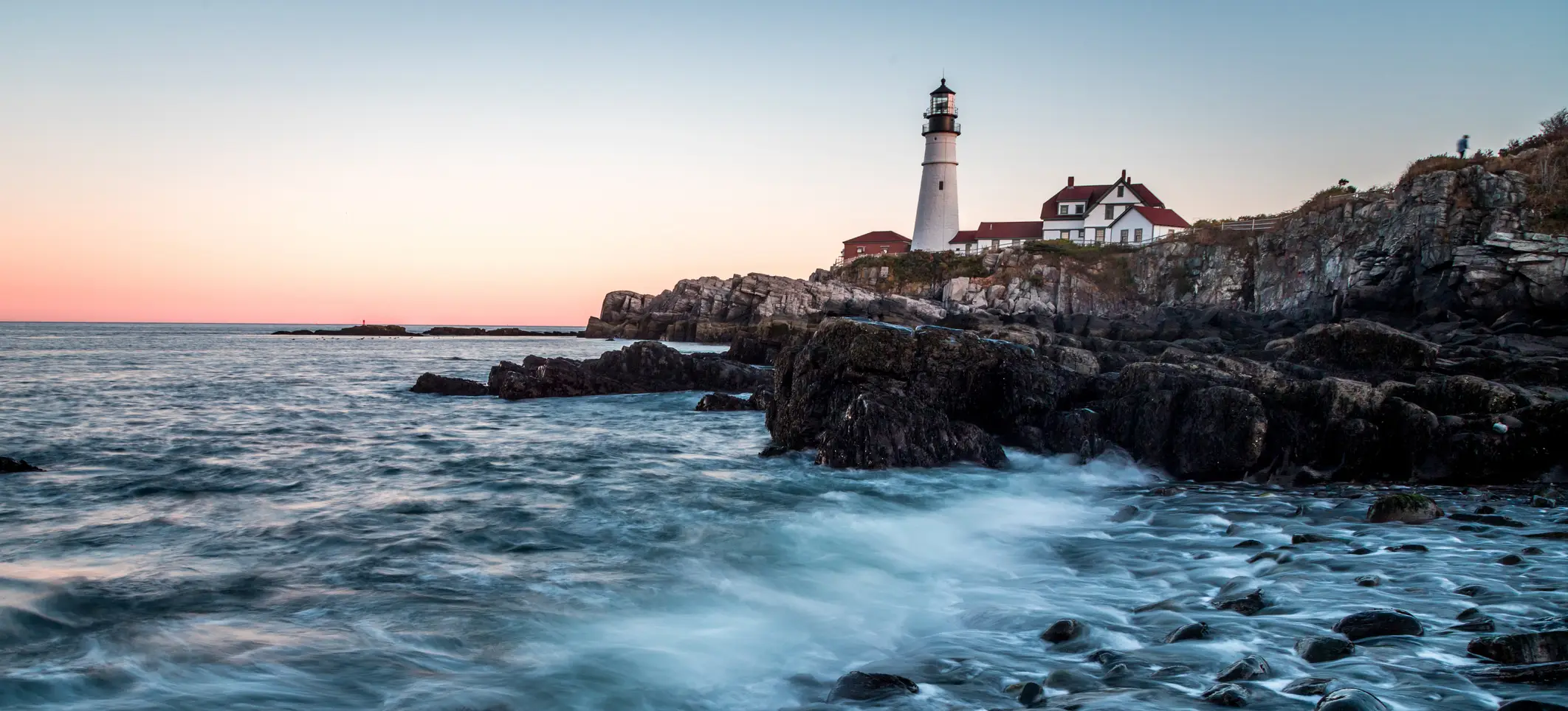 Portland Head Light above the rocky Maine coastline at sunset